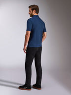 Polo Alpinestars Impetus Sport, polo de manga curta azul marinho, vista lateral e traseira no modelo, combinado com calças pretas e sapatilhas pretas, vestuário desportivo casual de estilo de vida motorsport