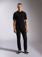 Polo Alpinestars Endeavor Classic, polo de manga curta em piqué, preto, pequeno logótipo Astars branco no peito, gola e punhos canelados, usado por modelo com calças pretas e sapatilhas, streetwear casual de desportos motorizados