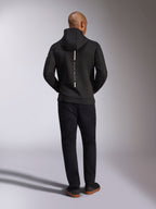 Alpinestars Insight Hoodie, Black, rear view on model, featuring a vertical white back stripe logo with "Racing Ahead" text, casual sportswear hoodie in tri-blend double face fleece, paired with black pants.