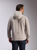 Alpinestars Insight Hoodie em Cement, vista traseira de modelo a usar uma sweatshirt cinzenta clara com capuz, apresenta um logótipo de risca vertical preta com o texto 'RACING AHEAD', hoodie casual de lã de dupla face inspirado no desporto motorizado.