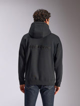 Sweatshirt com capuz Alpinestars Emergent Oversized, vista traseira de uma sweatshirt preta num modelo, com logótipo Alpinestars bordado nas costas, corte oversized, estilo casual combinado com calças de ganga escuras