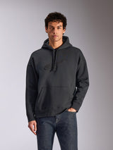 Alpinestars Emergent Oversized Hoodie, sweatshirt com capuz preta, modelo masculino a usar hoodie oversized em fleece, logótipo Astars com bordado 3D tonal, bolso canguru, capuz com cordão, streetwear casual inspirado no desporto motorizado