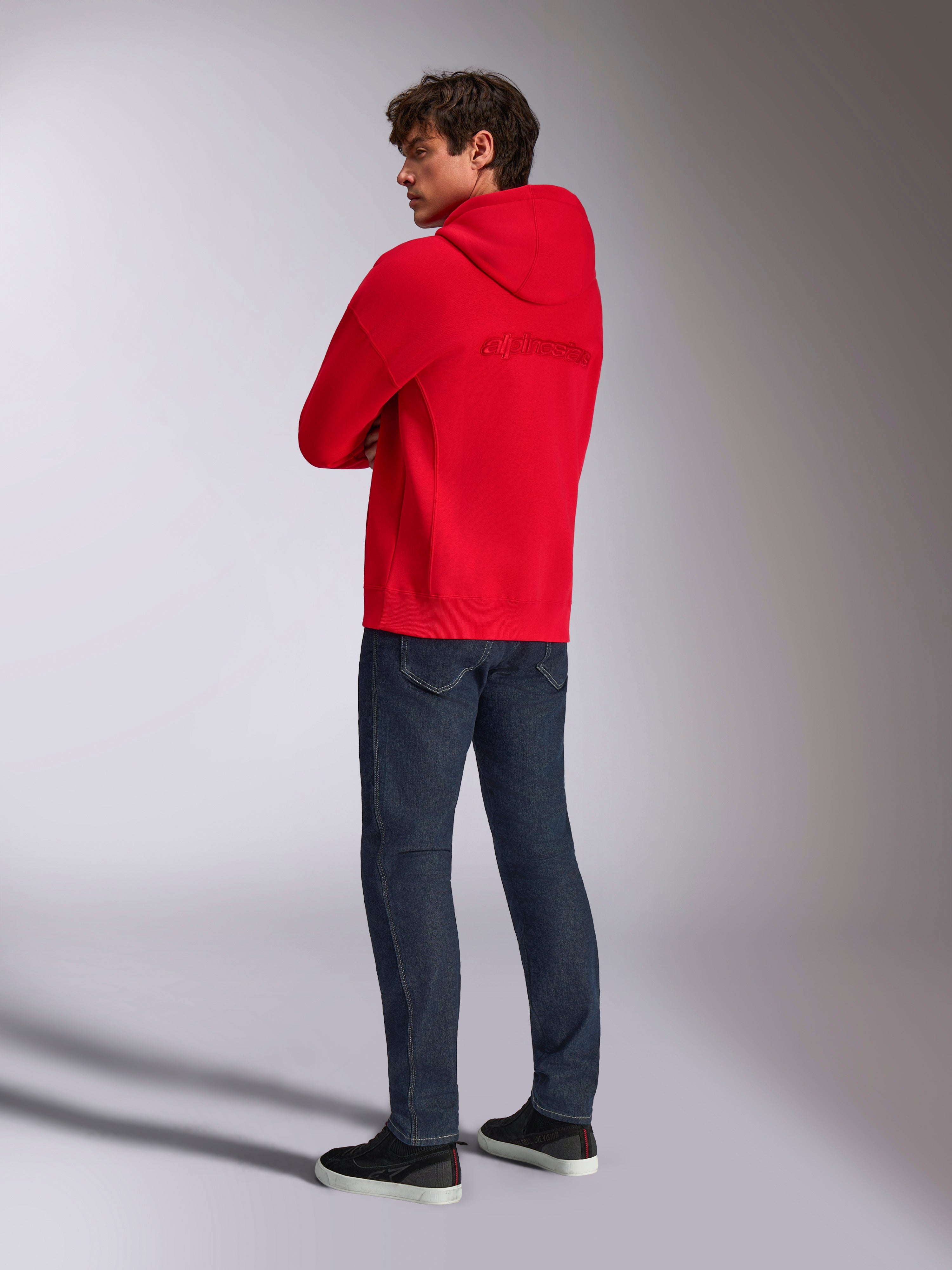 Alpinestars Emergent Oversized Hoodie, vermelho, vista traseira com logótipo Alpinestars bordado nas costas, corte oversized, usado com calças de ganga azul-escuro e ténis pretos, estilo casual lifestyle