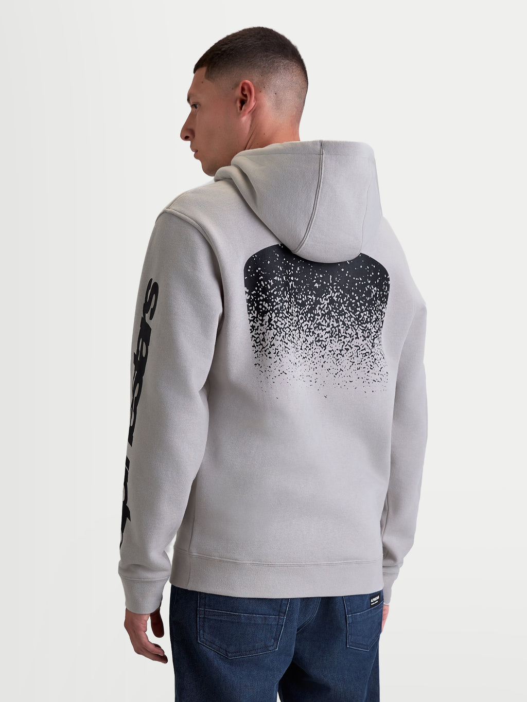 Alpinestars camisola com capuz Obsessed, camisola em fleece para homem em cinzento cimento, com grande gráfico traseiro preto em gradação inspirado em MX e marca na manga, vista traseira no modelo, vestuário casual motorsport.