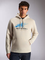 Alpinestars Pulse Hoodie, streetwear casual, cor areia, logótipo frontal Astars Combo em azul e cinzento com efeito de desvanecimento speed line e texto 'Racing Ahead', capuz com cordões, bolso canguru, usado por um modelo com calças de ganga escuras