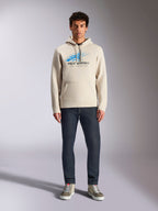 Alpinestars Pulse Hoodie, Off White, camisola de manga comprida com capuz e cordão, logótipo Astars Combo azul e preto com efeito de desvanecimento speed line, combinada com calças de ganga escuras e sapatilhas, streetwear casual de desportos motorizados