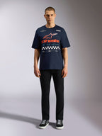 T-shirt Alpinestars Aplomb Oversized CSF, t-shirt de manga curta azul marinho, logótipo grande no peito com gradiente laranja e vermelho e padrão axadrezado, usada por modelo com calças pretas e sapatilhas, streetwear casual de inspiração motorsport