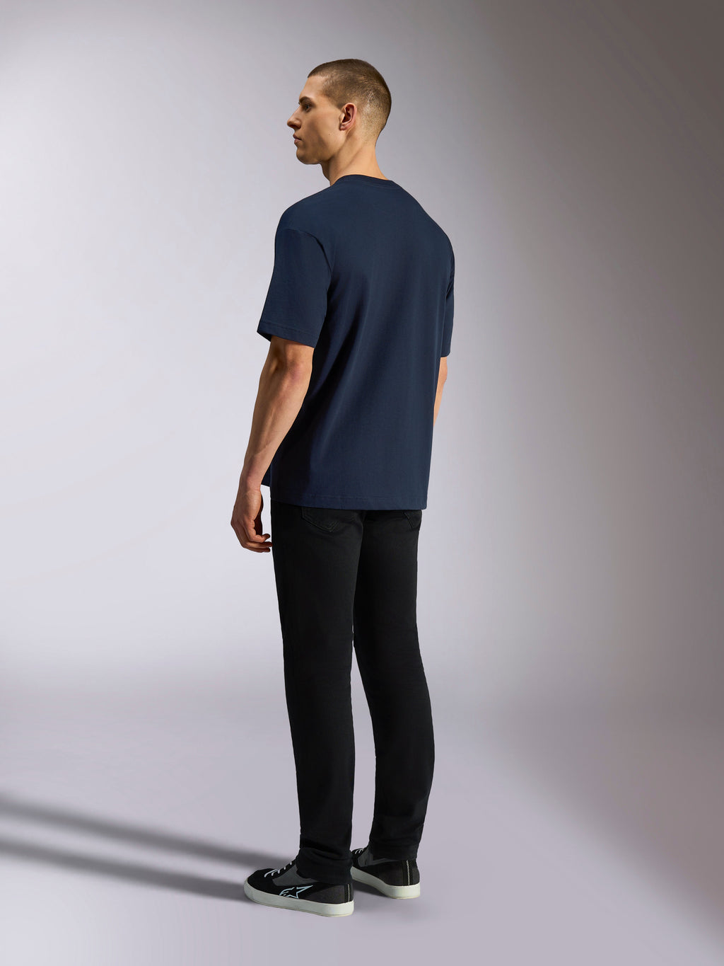 Alpinestars Aplomb Oversized CSF Tee, t-shirt de manga curta, azul-marinho, vista traseira no modelo, usada com calças pretas e sapatilhas, streetwear casual inspirado no desporto motorizado