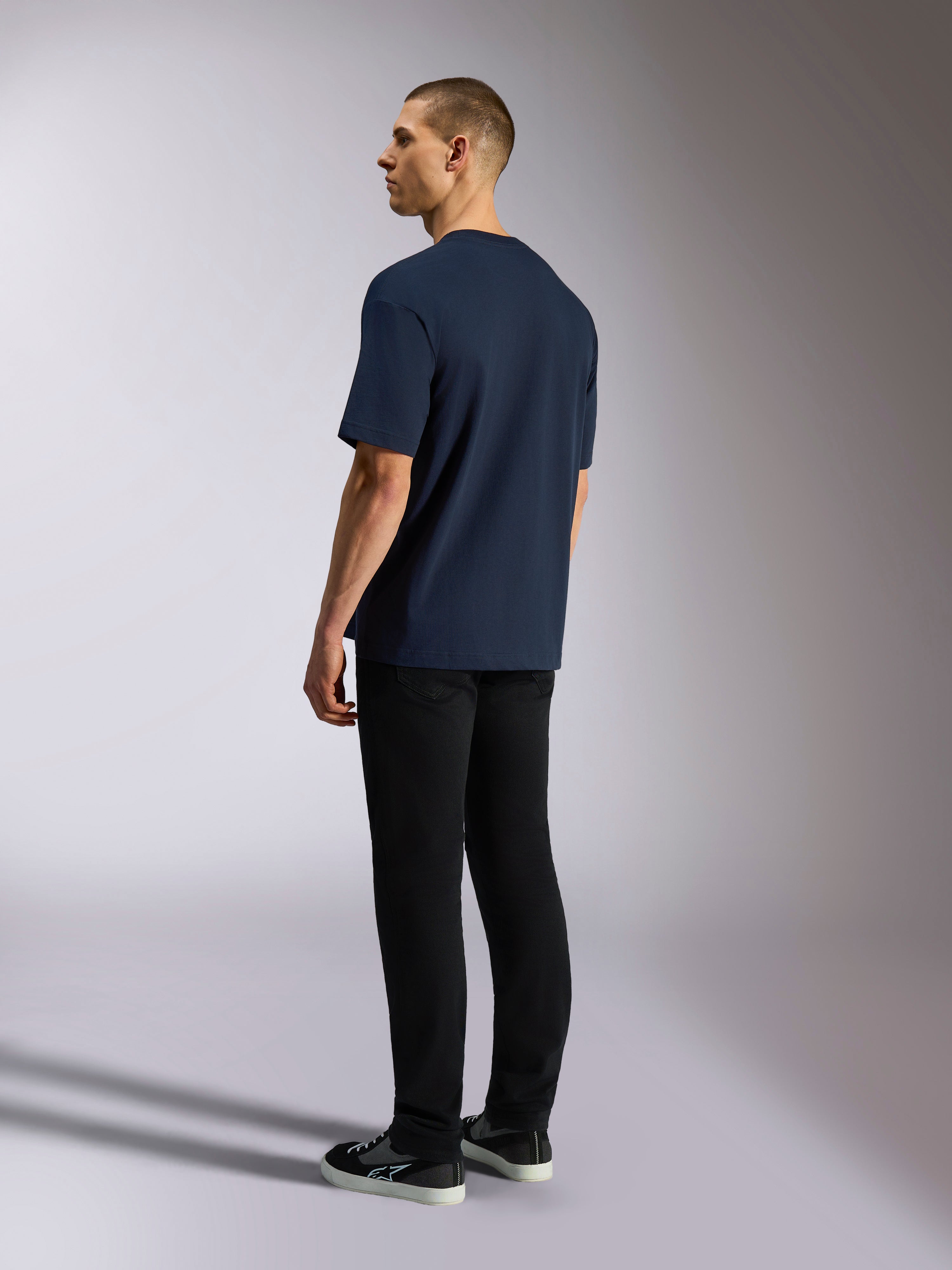 Alpinestars Aplomb Oversized CSF Tee, t-shirt de manga curta, azul-marinho, vista traseira no modelo, usada com calças pretas e sapatilhas, streetwear casual inspirado no desporto motorizado