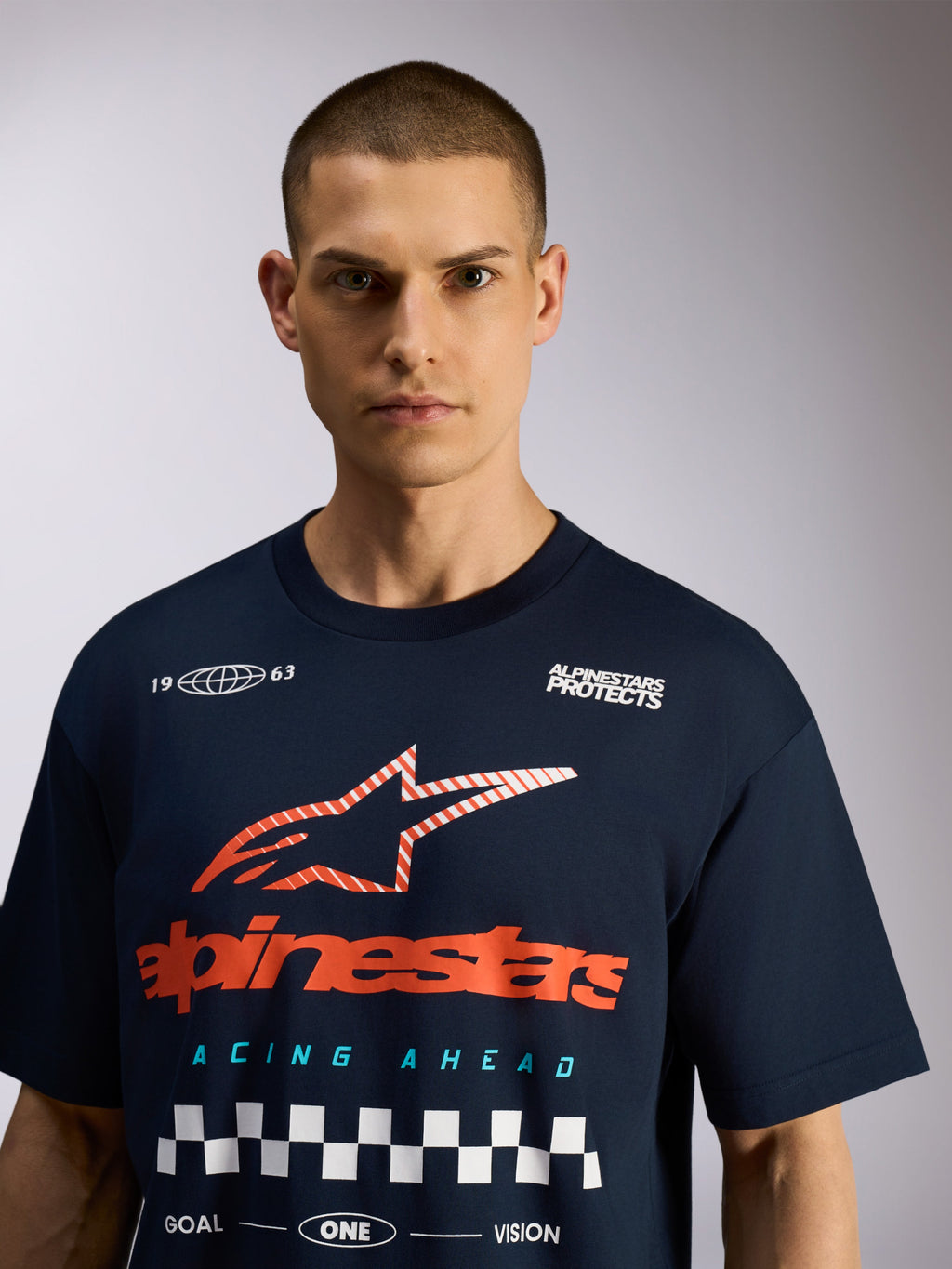 Alpinestars Aplomb Oversized CSF Tee, t-shirt de manga curta azul marinho, gráfico grande no peito com logótipo vermelho e padrão axadrezado branco, estilo casual streetwear inspirado nos desportos motorizados