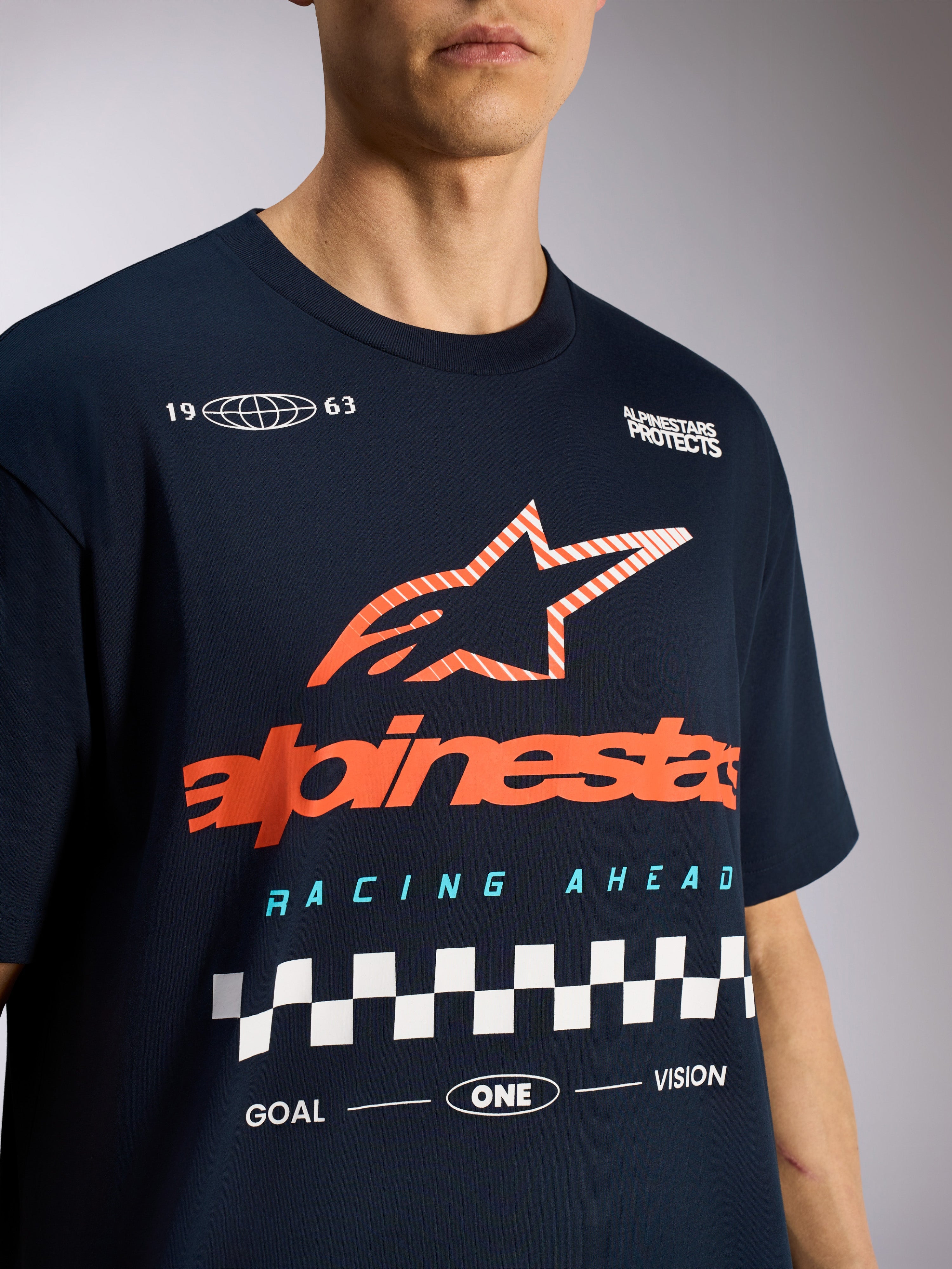 Alpinestars Aplomb Oversized CSF Tee, t-shirt de manga curta, azul marinho, com logótipo de estrela Astars grande em cor de laranja às riscas e grafismo de corrida em xadrez, roupa desportiva casual de desporto motorizado