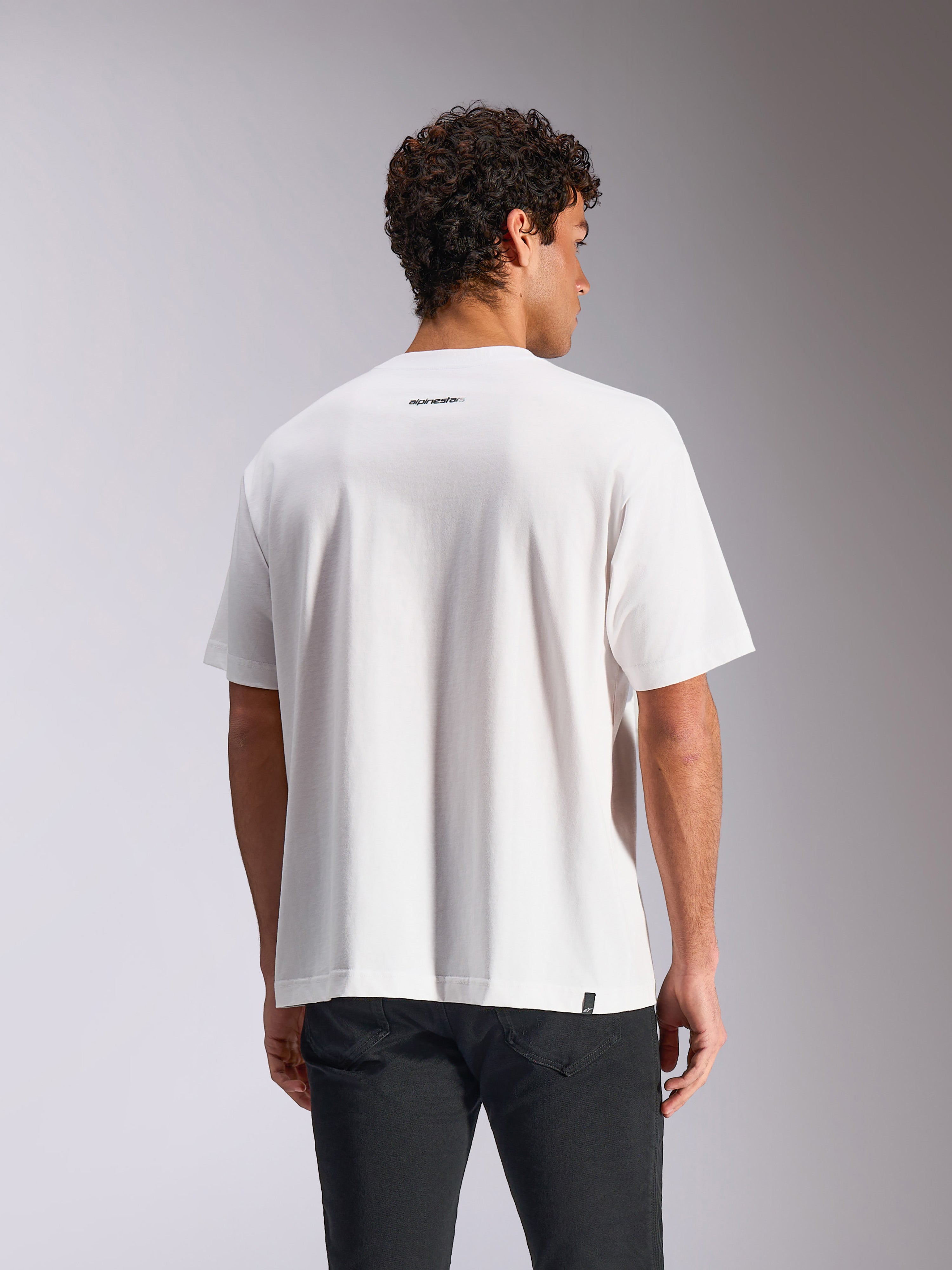 Alpinestars Focused Oversized CSF Tee, T-shirt de manga curta, branca, vista traseira no modelo a mostrar um pequeno logótipo da palavra Alpinestars a preto abaixo do decote, corte oversized descontraído, streetwear casual