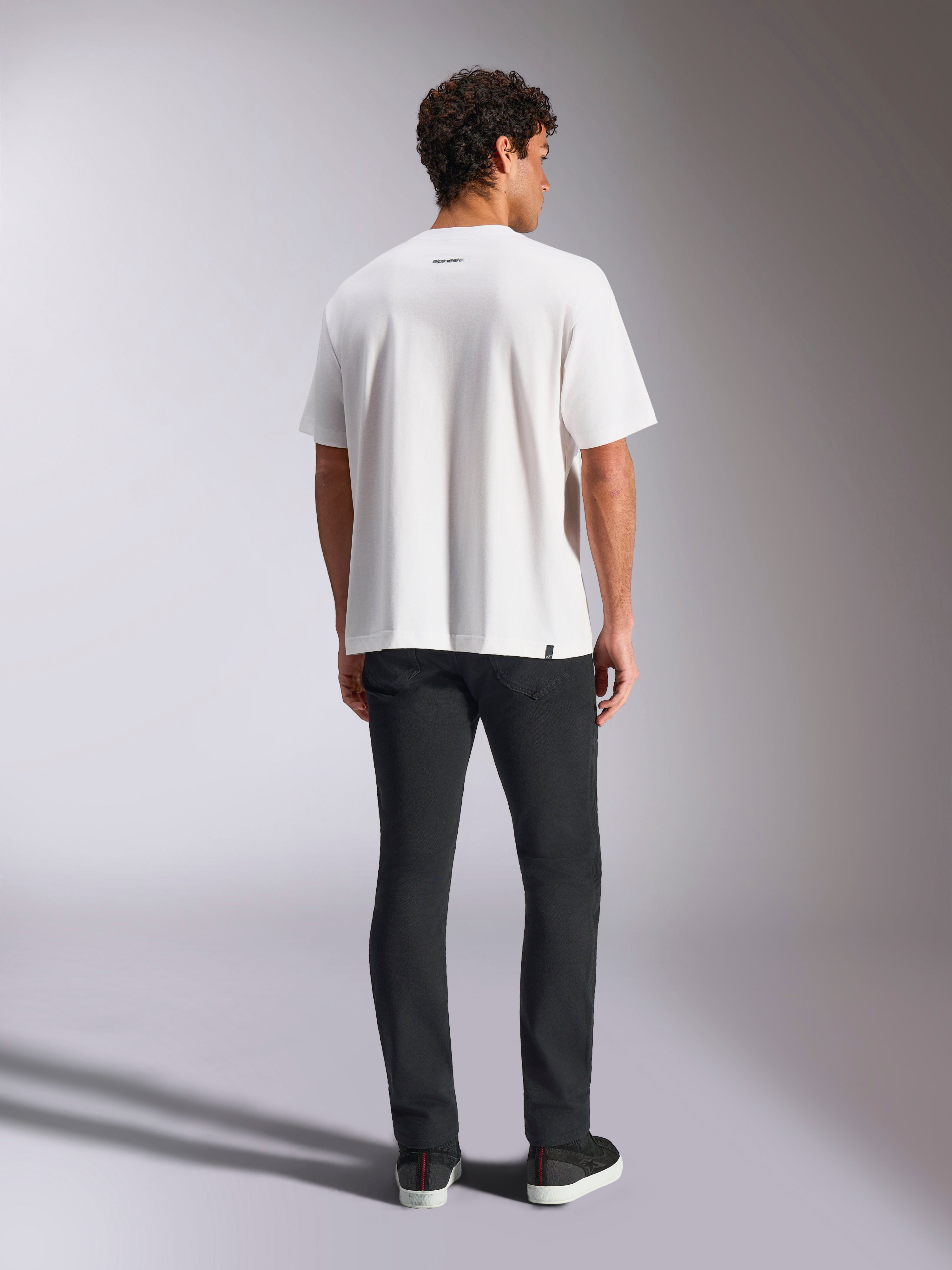 T-shirt Alpinestars Focused Oversized CSF, T-shirt de manga curta, branca, com um pequeno logótipo da palavra Alpinestars na parte superior das costas, corte oversized relaxado, estilo streetwear casual de desportos motorizados