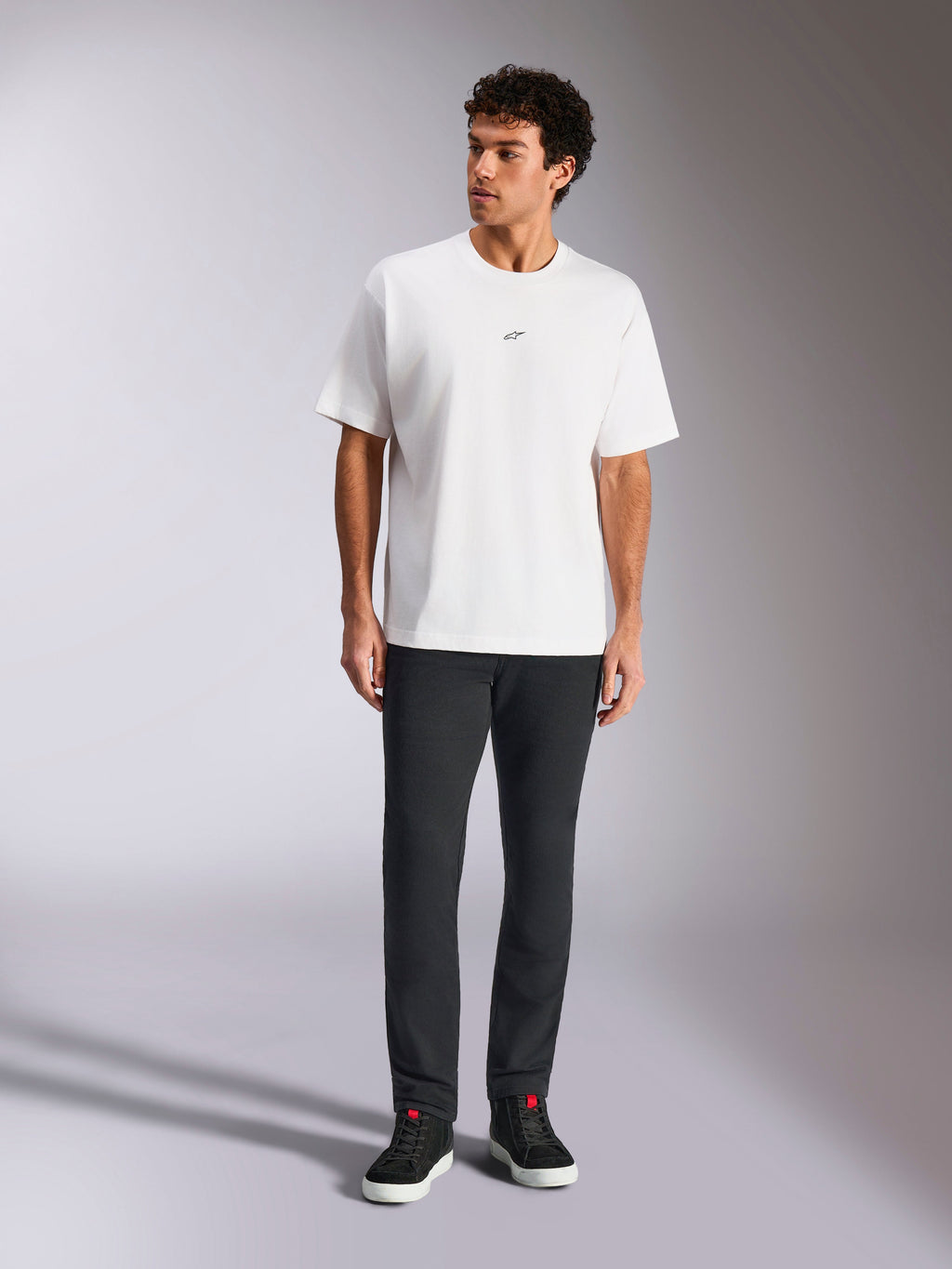 T-shirt Alpinestars Focused Oversized CSF, t-shirt de manga curta, branca, pequeno logótipo Astars preto no peito, estilo streetwear casual, usada por um modelo com calças escuras e sapatilhas de cano alto pretas