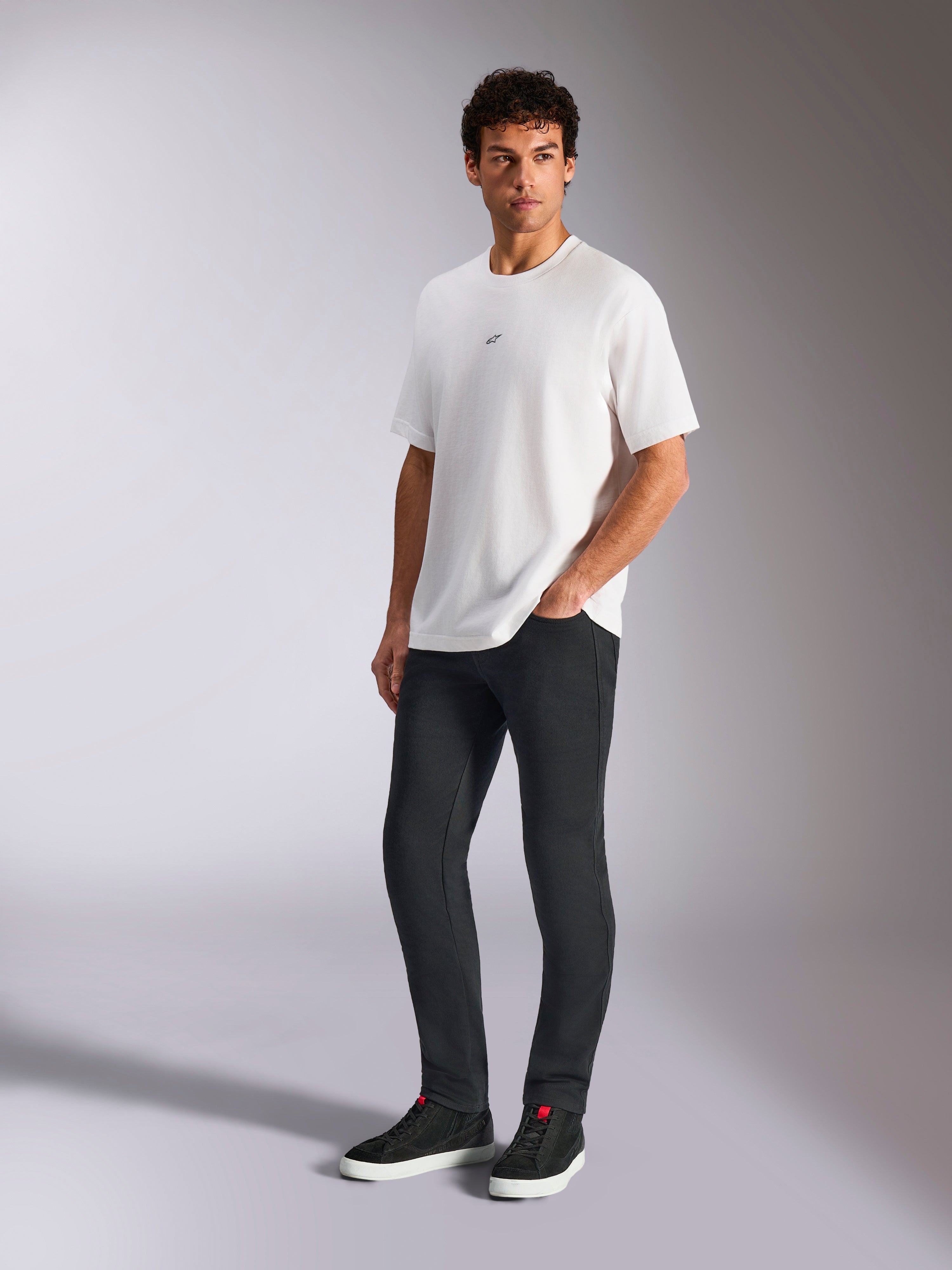 Alpinestars Focused Oversized CSF Tee, t-shirt de manga curta, branca, com um pequeno logótipo Astars preto no peito, usada por um modelo masculino com calças escuras e sapatilhas pretas, streetwear casual inspirado no desporto motorizado