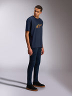 Alpinestars Alter Oversized CSF Tee, t-shirt de manga curta, azul-marinho, logótipo Astars amarelo e laranja, usada por um modelo com calças de ganga escuras e sapatilhas pretas, streetwear casual inspirado no desporto motorizado