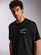 Um homem a usar a T-shirt Alpinestars Wild Oversized CSF, t-shirt preta de manga curta, com o logótipo Astars branco e grafismo multicolorido vibrante no peito, estilo casual motorsport streetwear