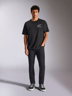 Alpinestars Wild Oversized CSF Tee, t-shirt de manga curta, preta, usada por um modelo com calças pretas e ténis, com um logótipo Astars branco e branding multicolorido vibrante, streetwear casual de desportos motorizados