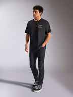 Alpinestars Wild Oversized CSF Tee, t-shirt de manga curta, preta, logótipo Astars multicolorido no peito, estilo streetwear casual, vestida por um modelo com calças pretas e sapatilhas de cano alto