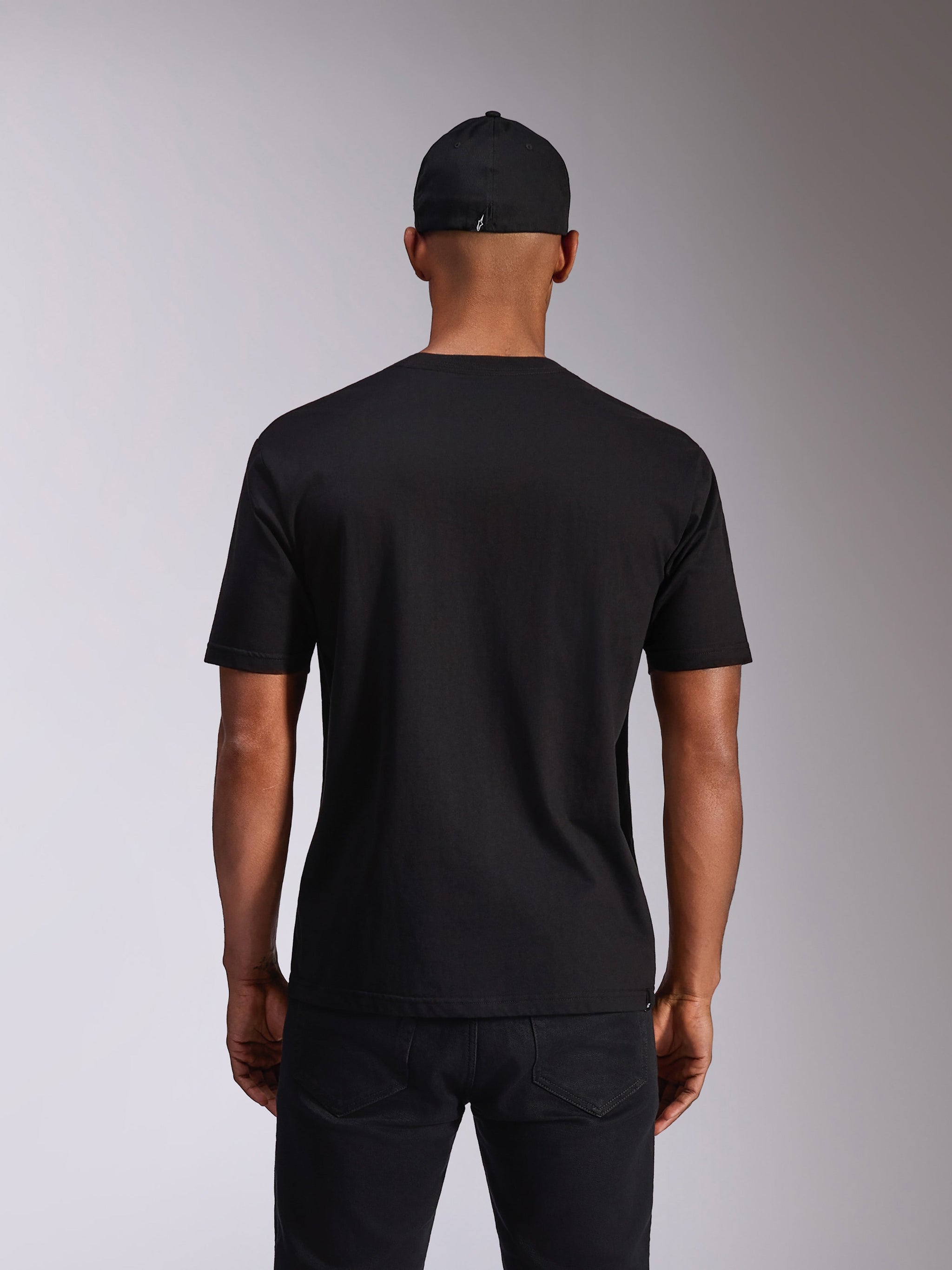 Alpinestars Ellipsoid CSF Tee, t-shirt de manga curta, preta, vista traseira no modelo, usada com um boné preto e calças escuras, streetwear casual inspirado no desporto motorizado
