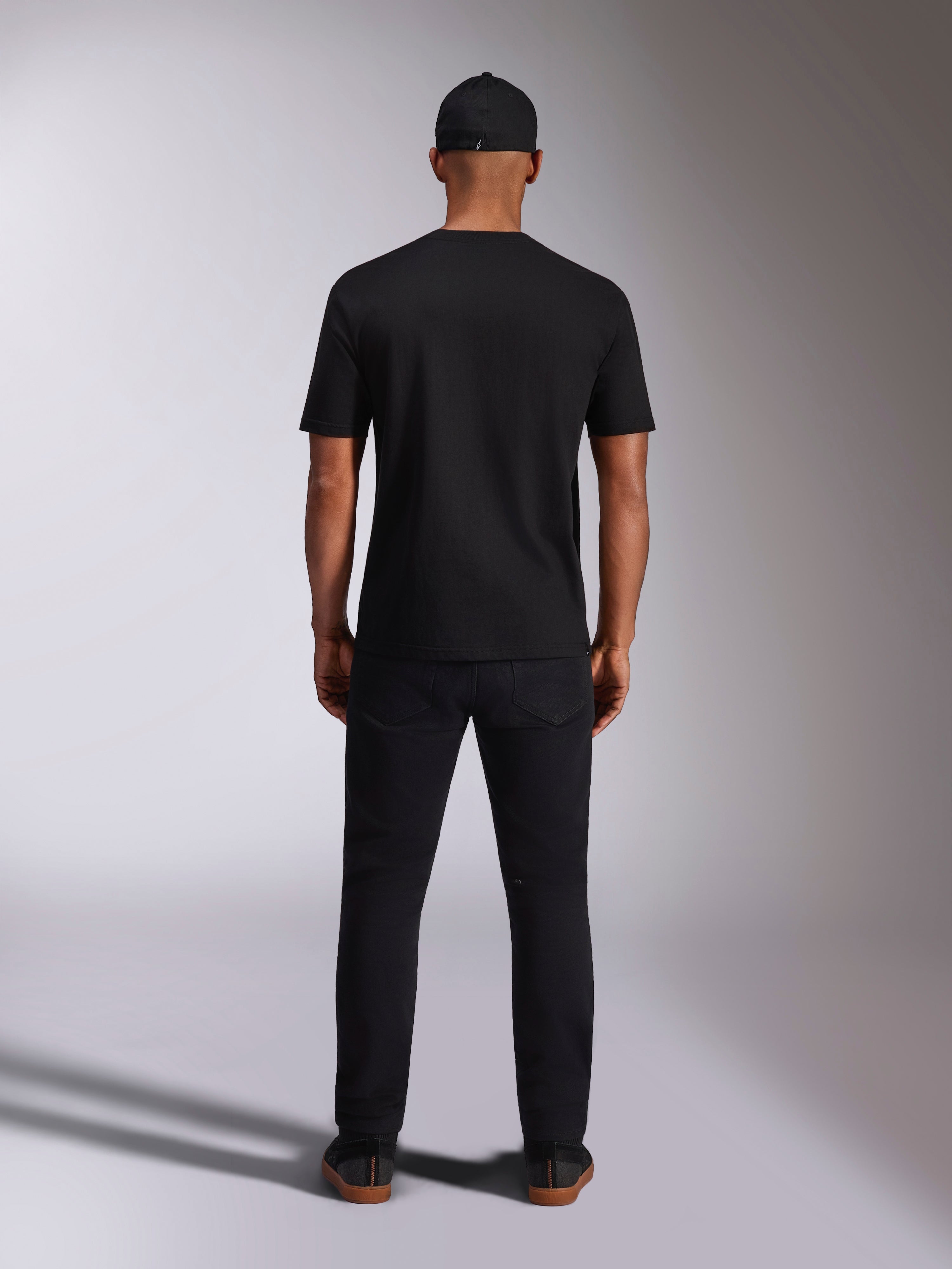 T-shirt Alpinestars Ellipsoid CSF, t-shirt de manga curta, preta, vista traseira usada por modelo com boné e calças pretas, streetwear casual inspirado no desporto motorizado