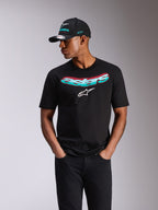 Alpinestars Ellipsoid CSF Tee, T-shirt de manga curta, preta, palavra Astars com gradiente azul-turquesa e rosa e logótipo branco, usada por um modelo com boné Alpinestars a condizer e calças de ganga pretas, streetwear casual de desportos motorizados