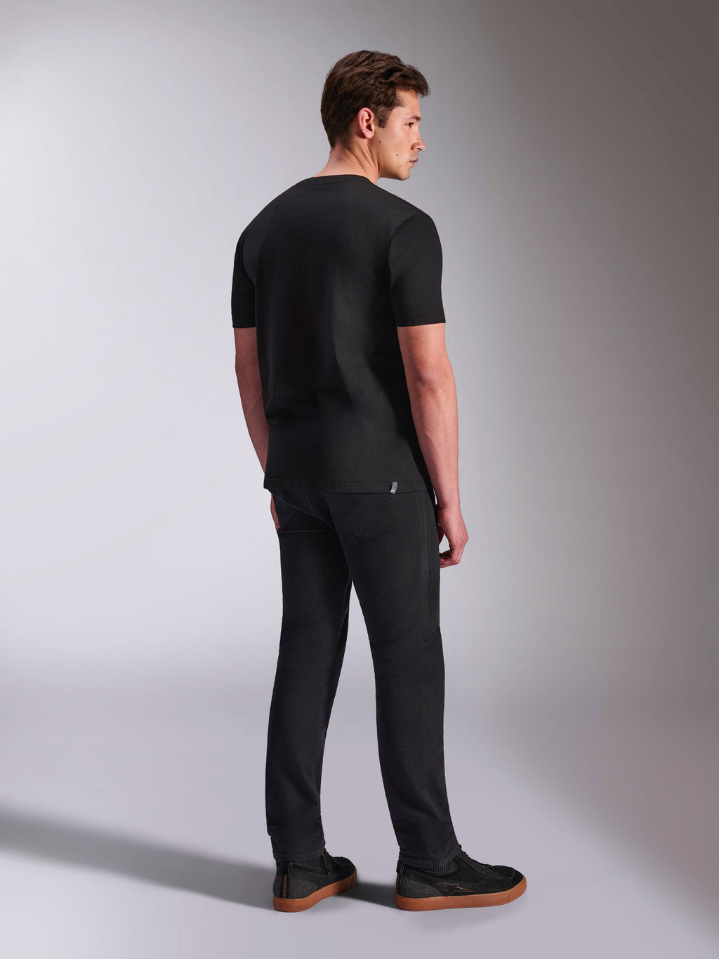 Alpinestars Abus CSF Tee, t-shirt de manga curta, preta, vista traseira num modelo masculino, streetwear casual de motorsport, combinada com calças escuras e sapatilhas