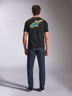 Alpinestars Angler CSF Tee, t-shirt de manga curta, preta, vista traseira do modelo a usar a t-shirt com logótipo de estrela Astars grande, vibrante e multicolor e texto 'RACING AHEAD', combinada com calças de ganga azul-escuro, streetwear casual de motorsport