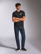 Alpinestars Angler CSF Tee, t-shirt de manga curta, preta, logótipo Astars vibrante e multicolor no peito, usada por modelo com os braços cruzados, calças de ganga escura e ténis pretos, streetwear casual de motorsport