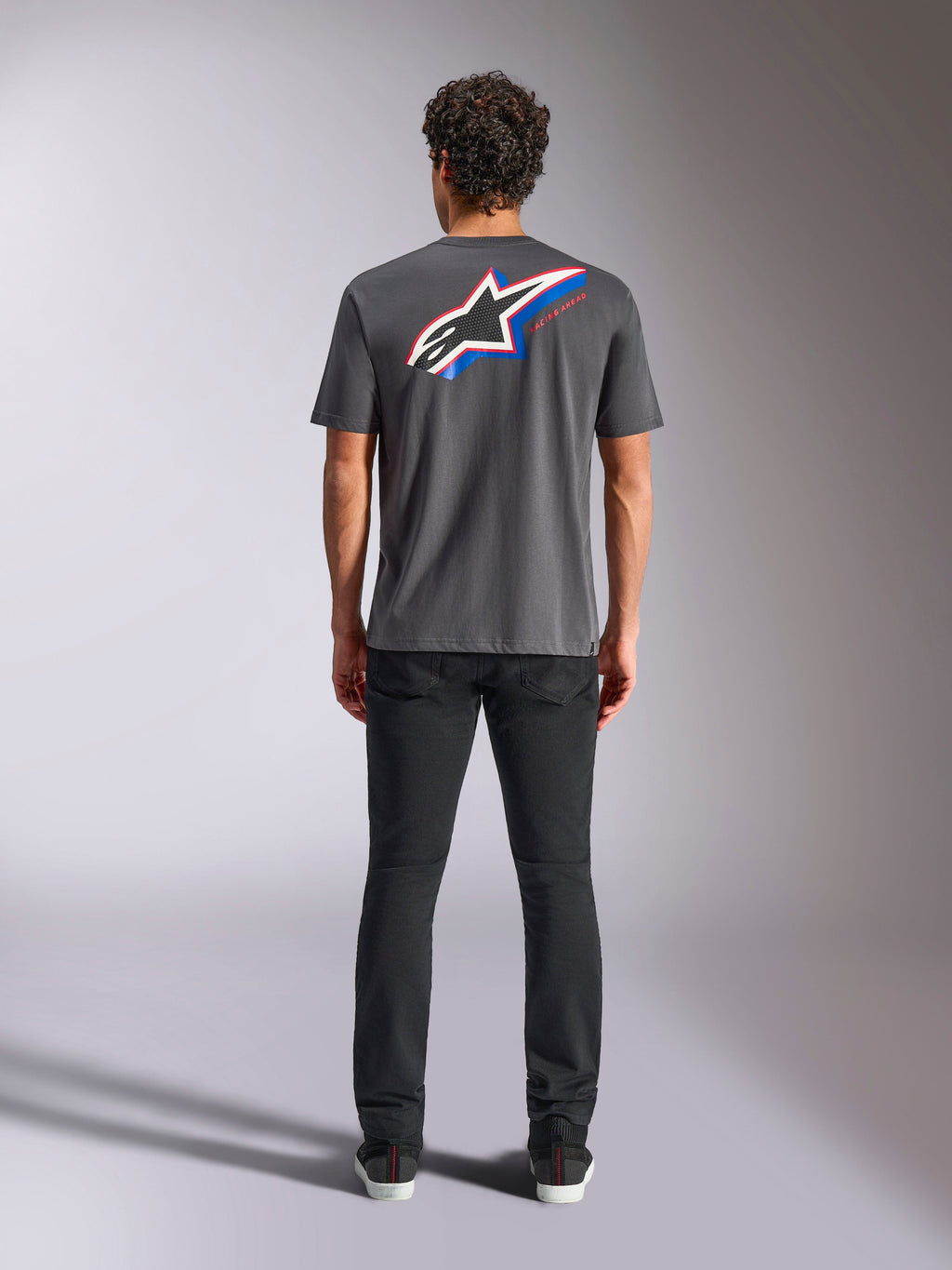 Alpinestars Angler CSF Tee, t-shirt de manga curta, cinzento escuro, logótipo Astars grande multicolorido nas costas com detalhes em vermelho e azul, vista traseira no modelo, streetwear casual de motorsport