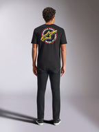 Alpinestars Aorbit CSF Tee, t-shirt de manga curta, preta, vista de costas num modelo com calças pretas, com um gráfico grande 'Always Fast Made to Last' e logótipo Astars amarelo, streetwear casual de desportos motorizados