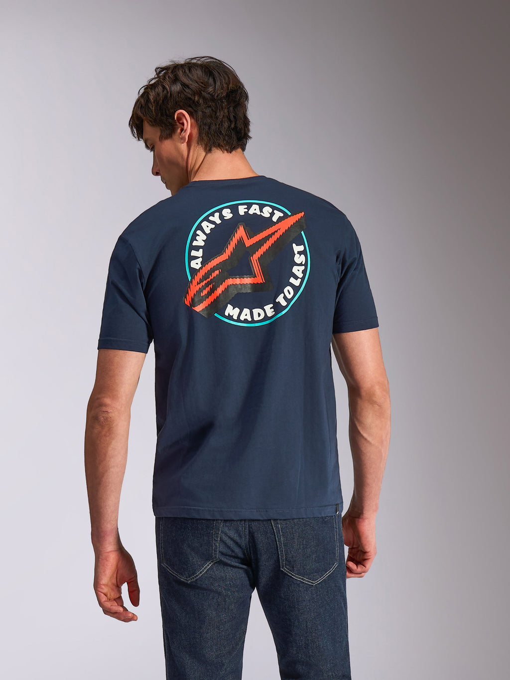 Alpinestars Aorbit CSF Tee, t-shirt de manga curta, azul marinho, vista traseira no modelo com gráfico circular 'Always Fast Made to Last' e logótipo Astars vermelho, streetwear casual inspirado no desporto motorizado