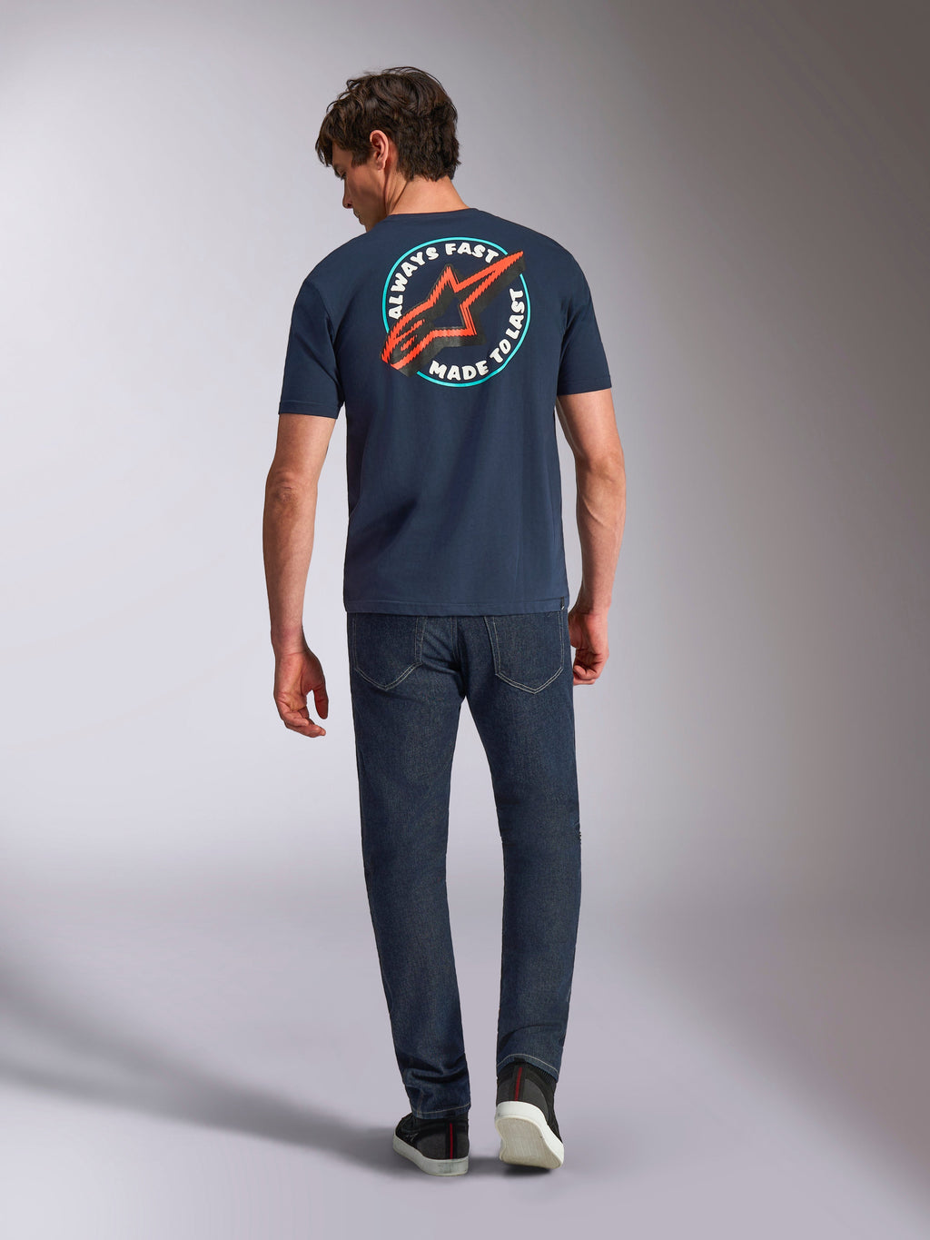 Alpinestars Aorbit CSF Tee, t-shirt de manga curta, azul-marinho, vista de costas num modelo com gráfico circular grande, logótipo Astars vermelho e texto 'Always Fast Made to Last', streetwear casual de desportos motorizados