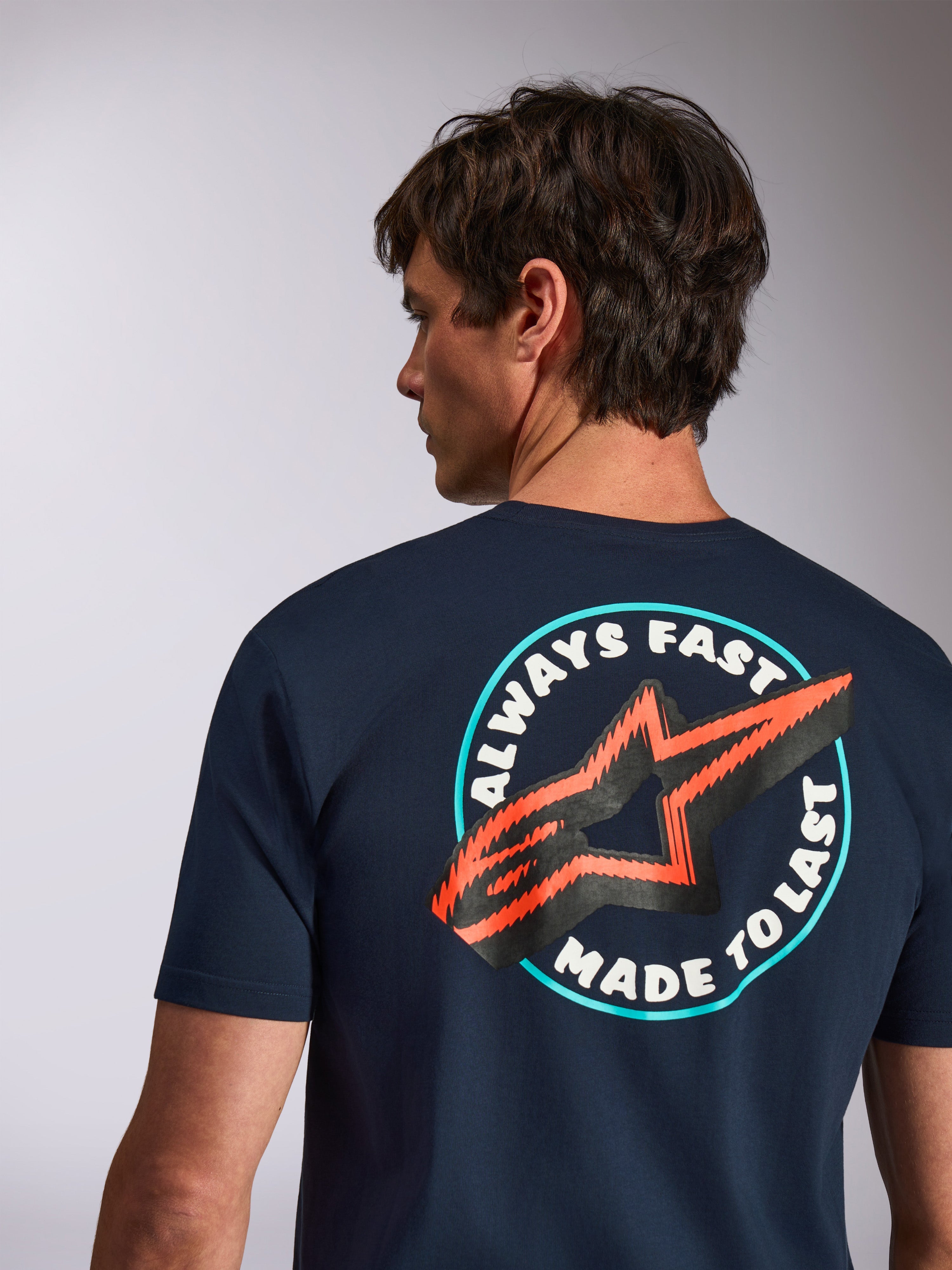 Alpinestars Aorbit CSF Tee, t-shirt de manga curta, azul marinho, vista traseira com o gráfico Always Fast Made to Last e logótipo de estrela laranja, streetwear casual de desporto motorizado