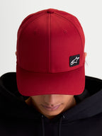 Alpinestars Chapéu Pivot, boné sportswear casual unissexo, vermelho escuro, tecido em sarja resistente com aba curva e coroa estruturada, pequeno patch preto do logótipo Astars bordado, vista no modelo.