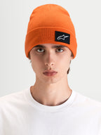 Alpinestars Augment Cuff gorro, gorro de sportswear descontraído em laranja vibrante com um patch tecido do logótipo Astars, usado por um modelo numa silhueta de ajuste profundo