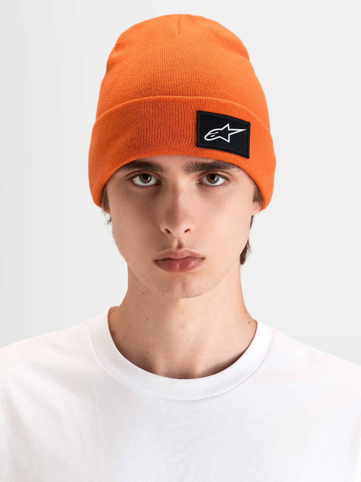 Alpinestars Augment Cuff gorro, gorro de sportswear descontraído em laranja vibrante com um patch tecido do logótipo Astars, usado por um modelo numa silhueta de ajuste profundo