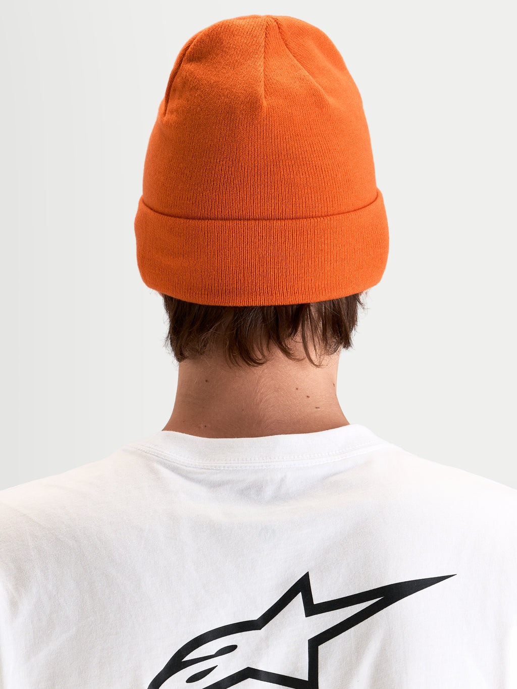 Alpinestars Augment Cuff gorro, gorro de malha laranja com silhueta de ajuste profundo e design com dobra, vista traseira num modelo a usar uma t-shirt branca com logótipo preto Astar