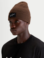Alpinestars Gorro Augment Cuff, gorro de malha sportswear, castanho, com patch de logótipo Alpinestars tecido em preto e branco na bainha, usado por um modelo