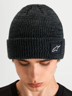 Gorro Unload Rib Cuff da Alpinestars, gorro de malha de inverno para desporto, cinzento melga, com dobra canelada e remate com o logótipo Alpinestars, visto num modelo num plano próximo do produto