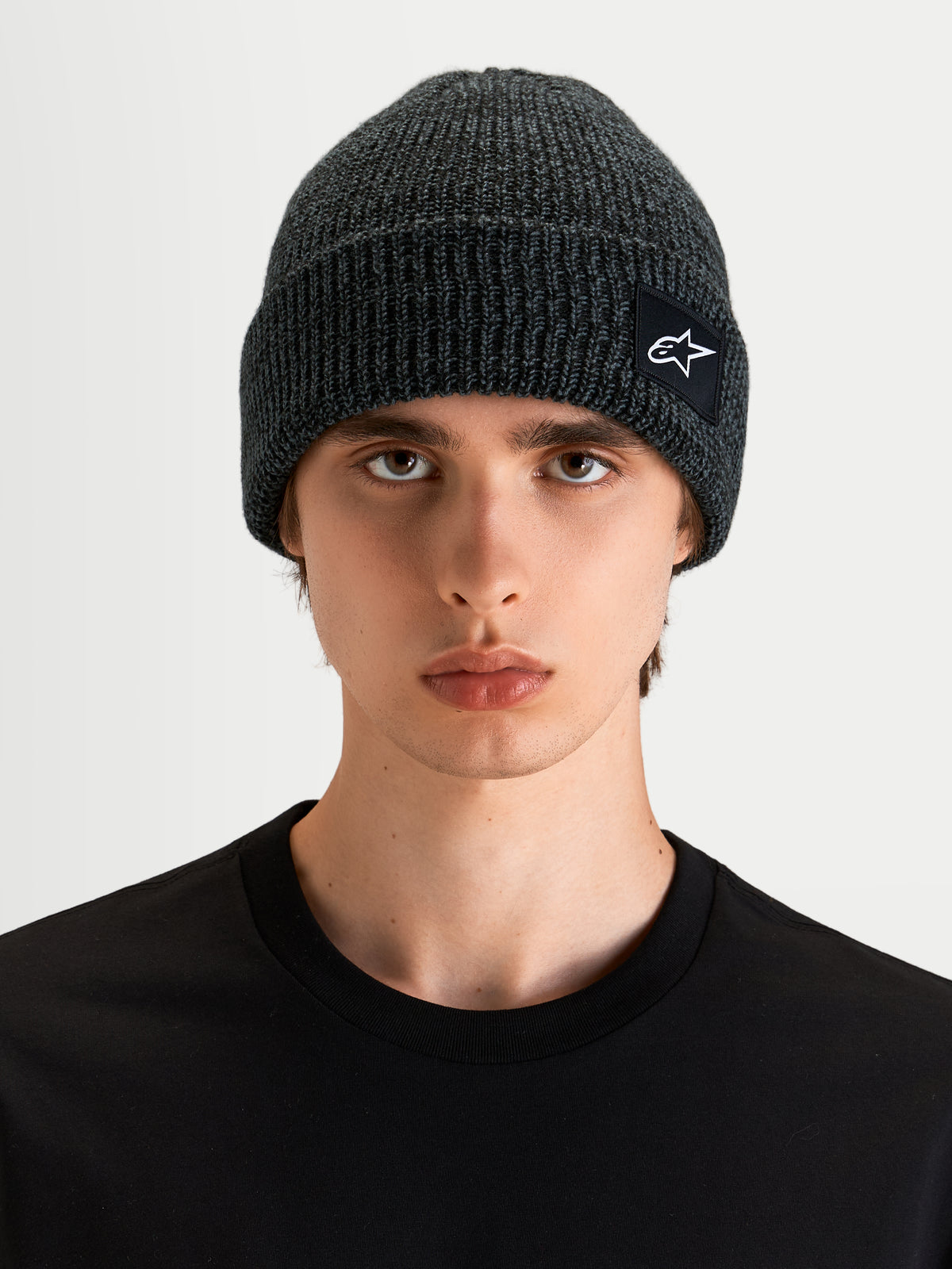 Alpinestars Unload Rib Cuff Beanie, sportswear knit beanie in charcoal melange, worn by a model, featuring a rib-knit design and SAstars woven patch logo