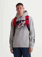 Alpinestars Mochila GFX Boss, mochila sportswear urbana de 20L, para homem e mulher, vermelha e preta, em poliéster 600D resistente. Vista frontal no modelo, apresentando alças de ombro ajustáveis em rede respirável e logótipo Astars em silicone em relevo.