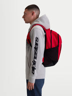 Alpinestars Mochila GFX Boss, mochila de uso diário sportswear, vermelha e preta, capacidade de 20L, construção em poliéster 600D com bolsos laterais em rede e alças almofadadas, mostrada num modelo para uso urbano.