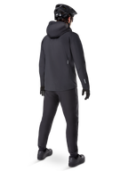 Alpinestars A-Dura Elite Waterproof Jacket, Black, rear view showing over-the-helmet hood and longer drop tail hem, paired with matching black MTB pants, gloves, and helmet for complete all-weather trail protection.