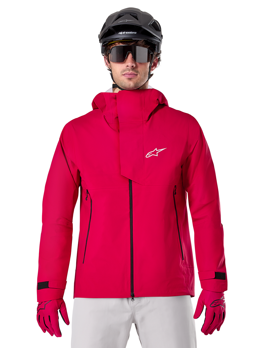 Alpinestars A-Dura Elite Waterproof Jacket, casaco de chuva para BTT, vermelho fluo, gola alta com logótipo Alpinestars branco, detalhes de fechos pretos, usado com luvas a condizer e capacete de ciclismo preto, equipamento técnico de ciclismo impermeável