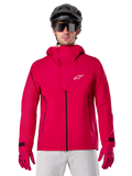 Alpinestars A-Dura Elite Waterproof Jacket, casaco de chuva para BTT, vermelho fluo, gola alta com logótipo Alpinestars branco, detalhes de fechos pretos, usado com luvas a condizer e capacete de ciclismo preto, equipamento técnico de ciclismo impermeável