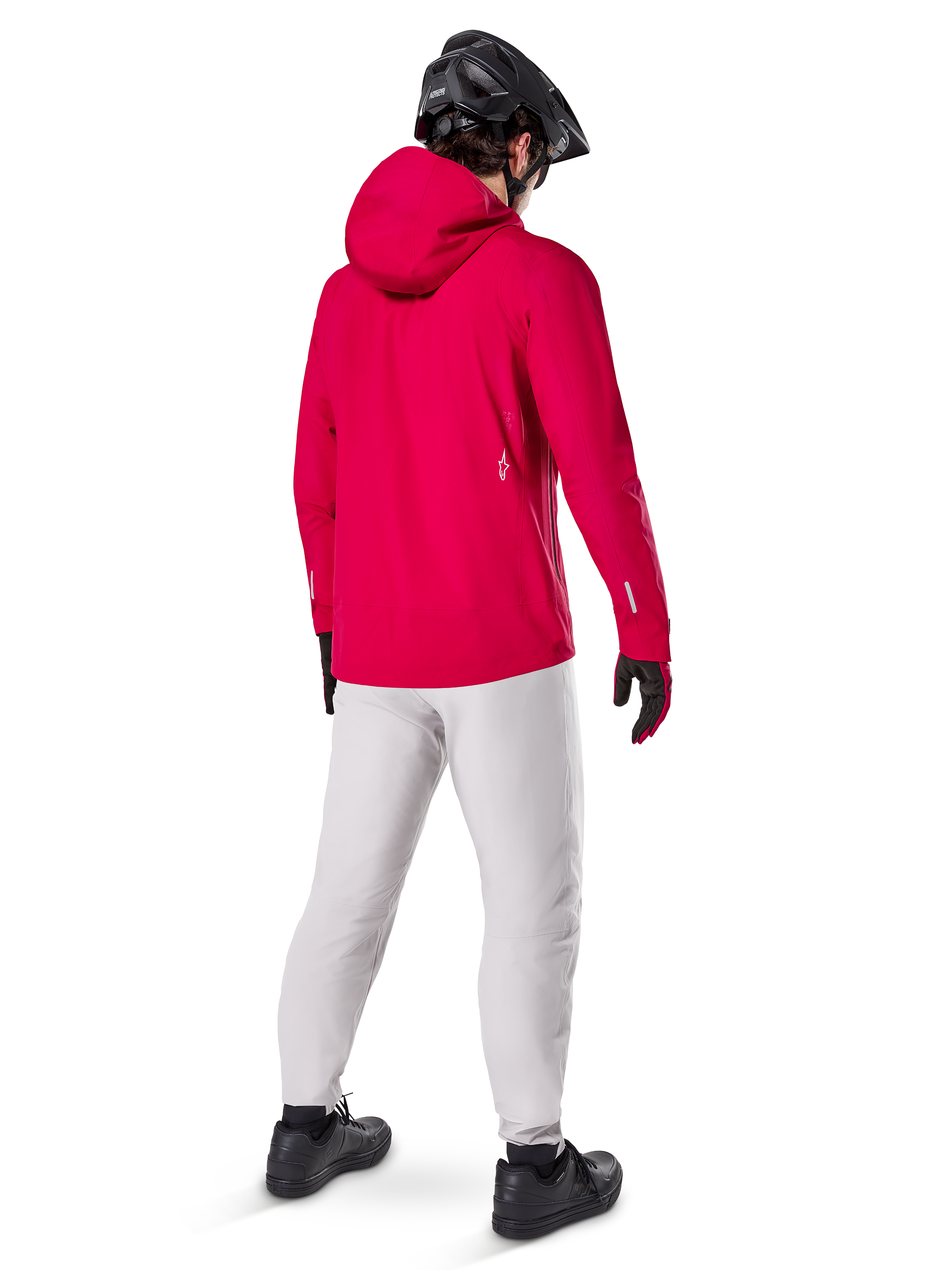 Casaco Impermeável Alpinestars A-Dura Elite, Vermelho Fluo, vista traseira de três quartos, usado com calças cinzento claro e capacete de BTT preto, inclui capuz e detalhes refletores, casaco de chuva de ciclismo de alto desempenho para trilhos