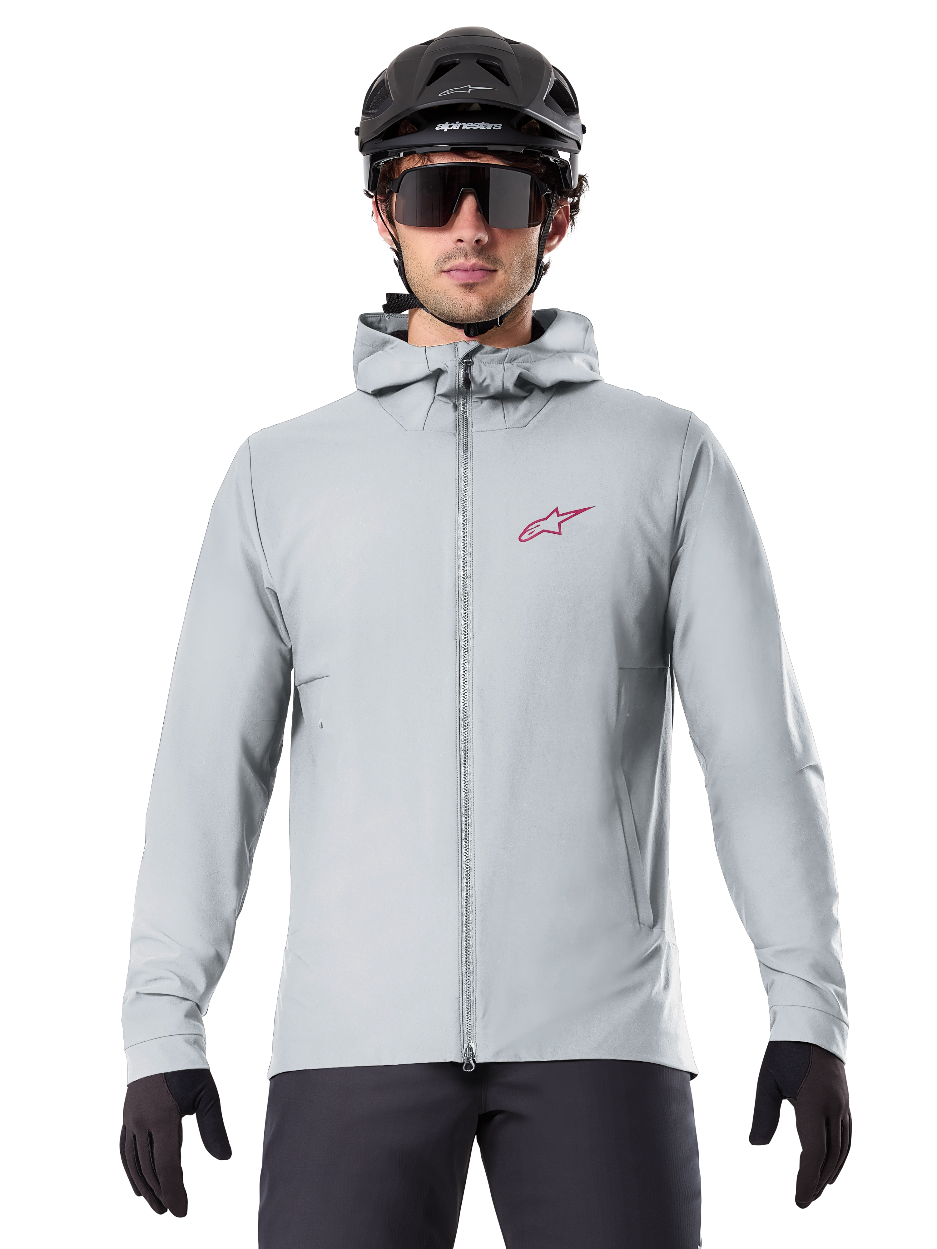 Alpinestars A-Dura Thermal Jacket em Titanium, casaco de ciclismo cinzento claro com capuz e logótipo de estrela vermelho no peito, usado por um ciclista com capacete de BTT preto, óculos de sol e luvas, equipamento térmico para mountain biking