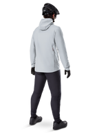 Casaco Térmico Alpinestars A-Dura em Titanium, vista traseira de ciclista masculino a usar casaco térmico cinzento claro com capuz, combinado com capacete de BTT preto, luvas pretas e calças cinzento-escuras, equipamento funcional de ciclismo de montanha.