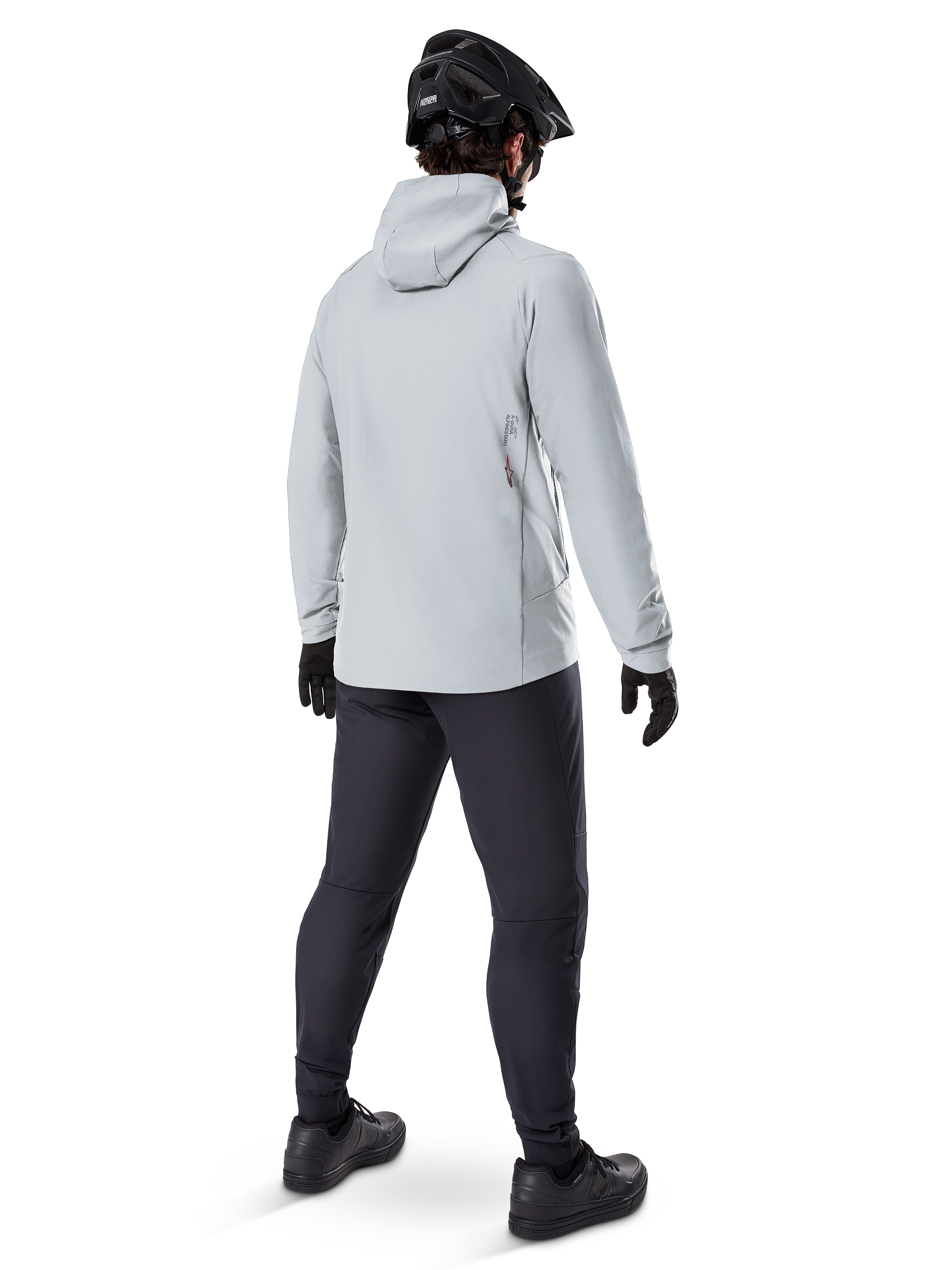 Casaco Térmico Alpinestars A-Dura em Titanium, vista traseira de ciclista masculino a usar casaco térmico cinzento claro com capuz, combinado com capacete de BTT preto, luvas pretas e calças cinzento-escuras, equipamento funcional de ciclismo de montanha.